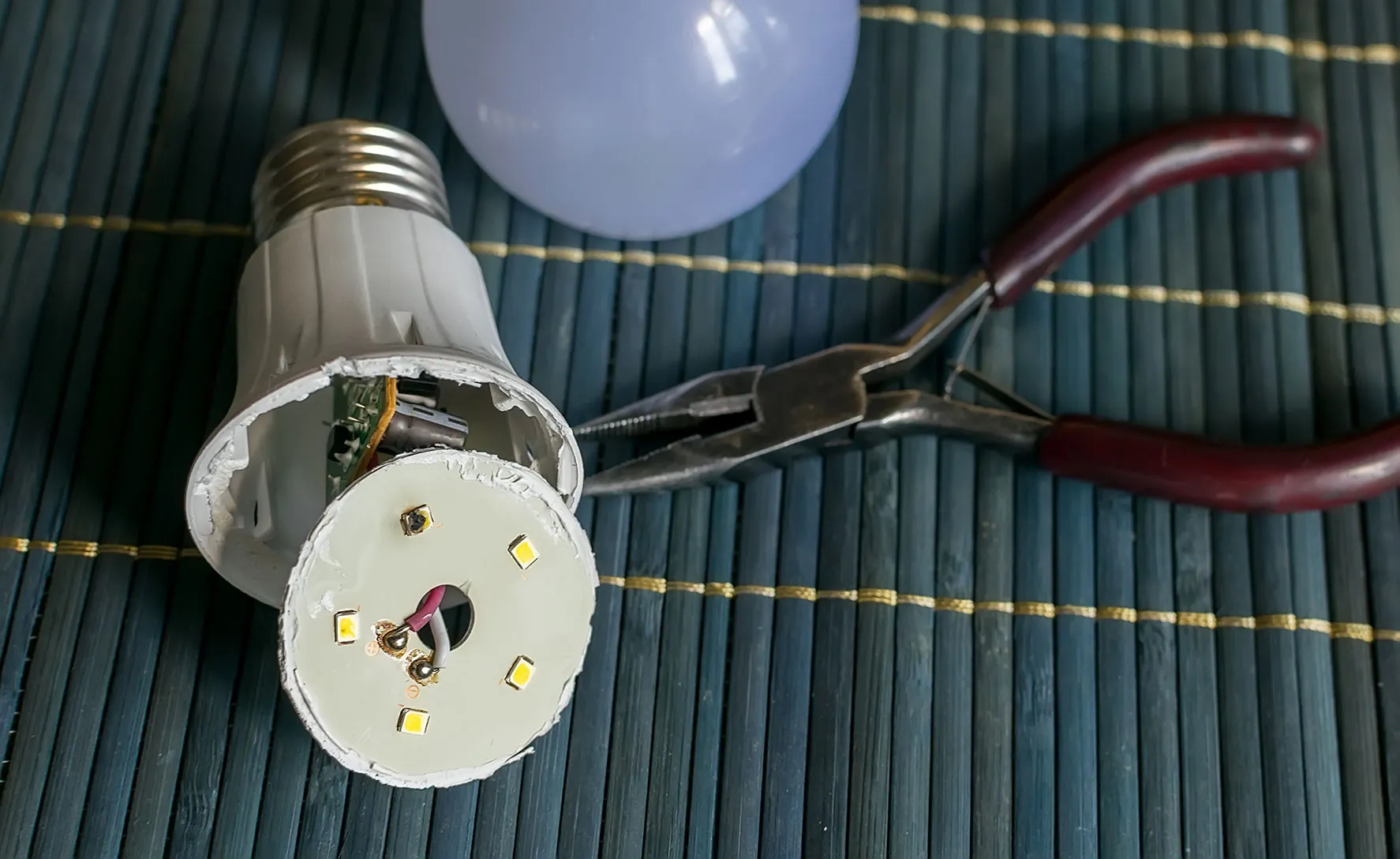 A pair of pliers and a light bulb on a mat.